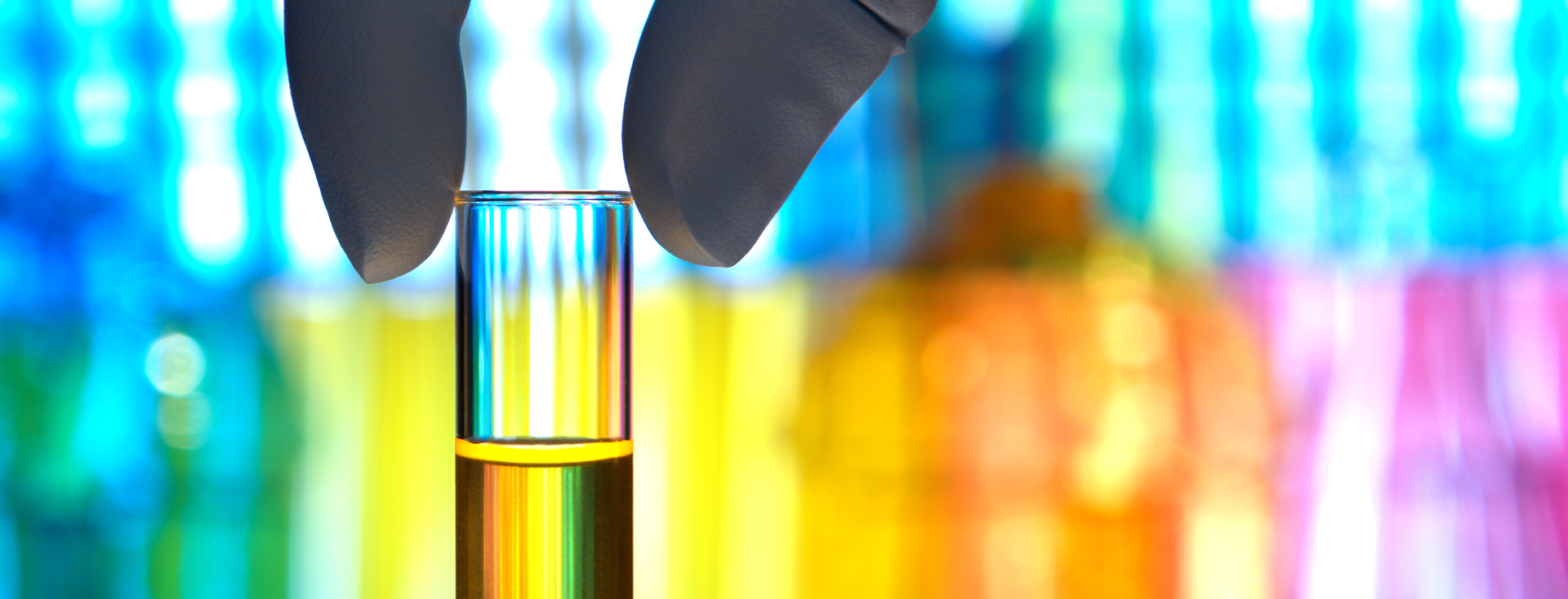 sample vessel with yellow liquid in front of a colourful laboratory background sample vessel with yellow liquid in front of a colourful laboratory background